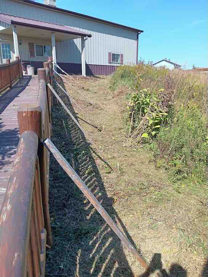 Wooden ramp access to building, surrounded by foliage.