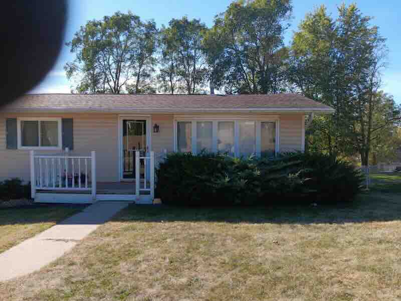 Single-story house with porch and shrubs.